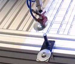 Robot tool approaching a washer and peg fixture mounted to an aluminum rail