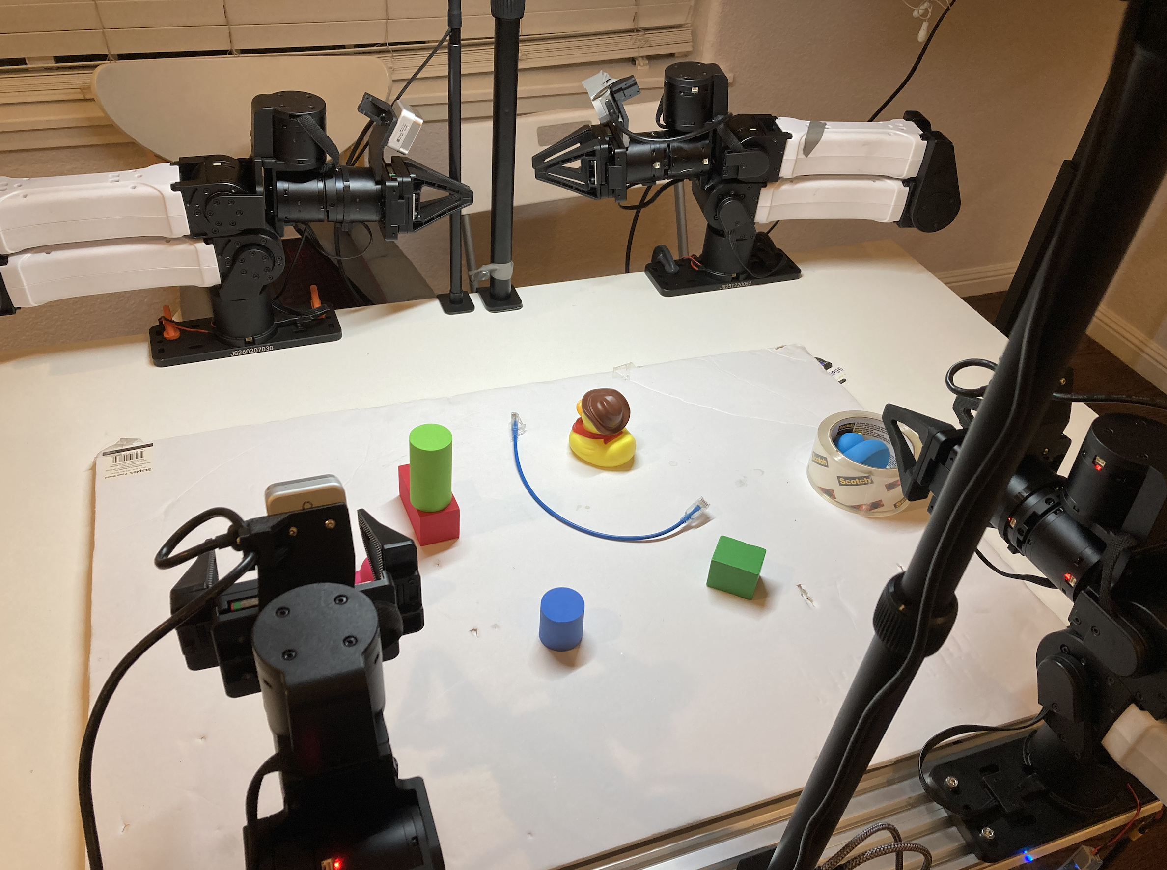 Robot arms around a tabletop with blocks, a cable, and other objects
