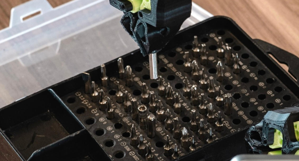 Robot gripper inserting a metal bit into one of many closely spaced holes